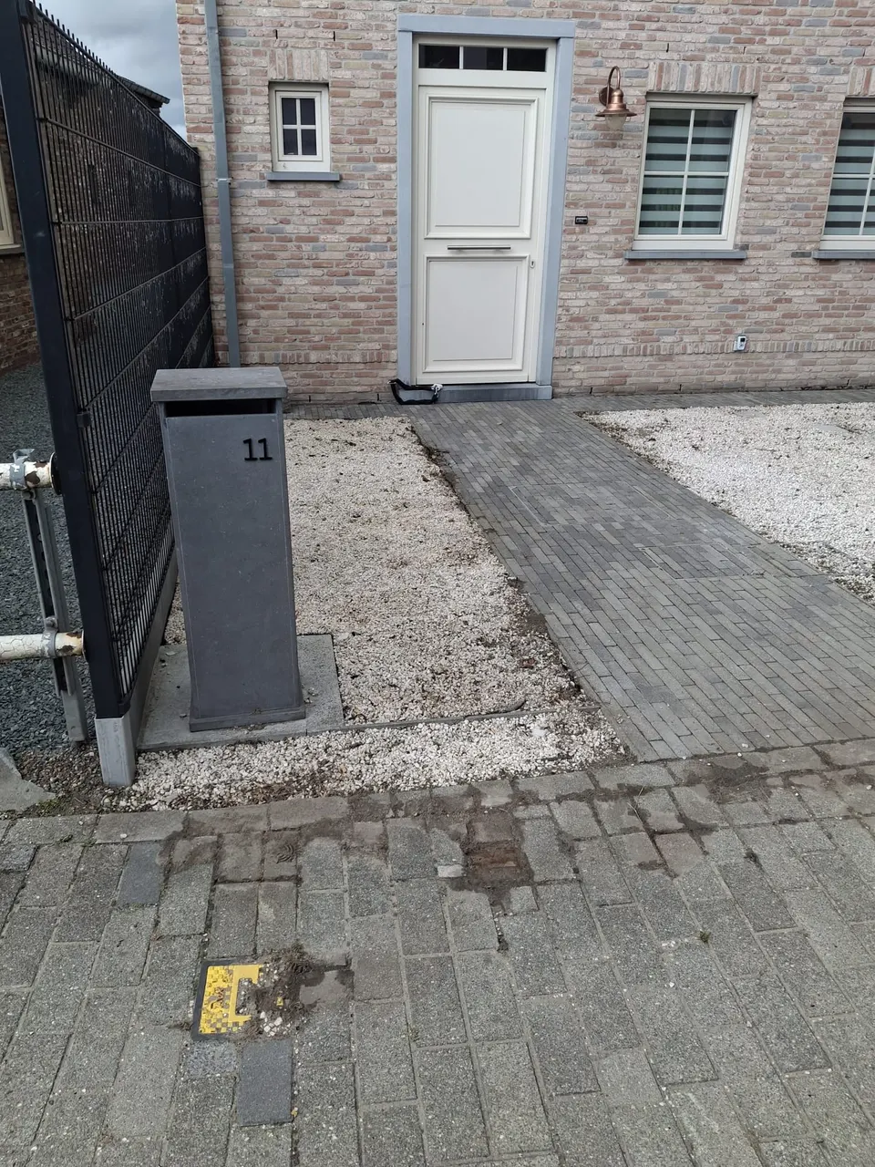 Dezelfde voortuin met wit grind en een klinkerpad, volledig onkruidvrij
