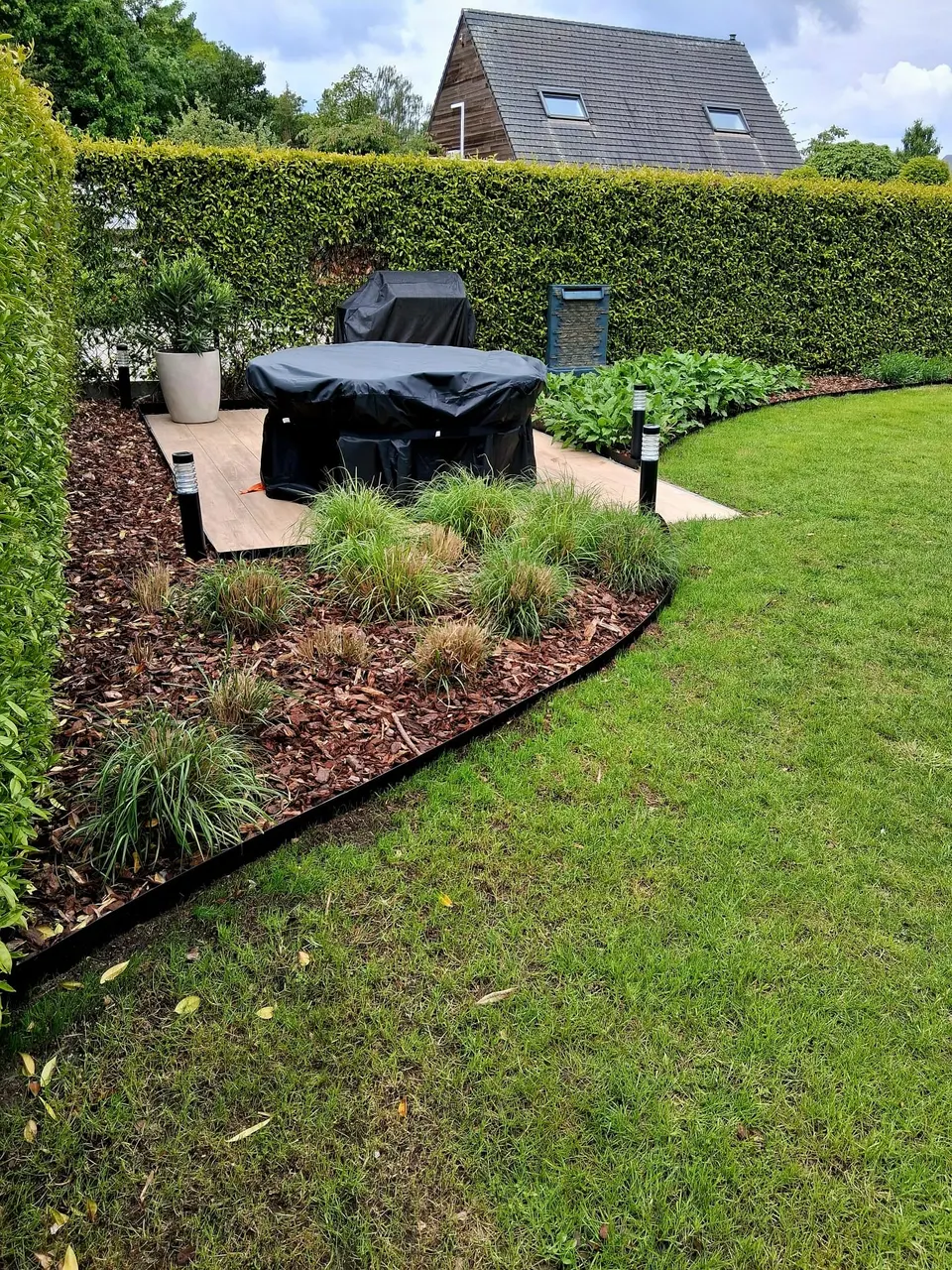 Gebogen border met cortenstalen afboording rond een terras